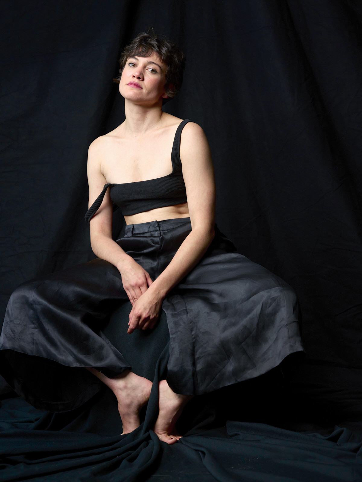 Milena Straube im schwarzen Satinrock sitzend, Fashion-Strecke