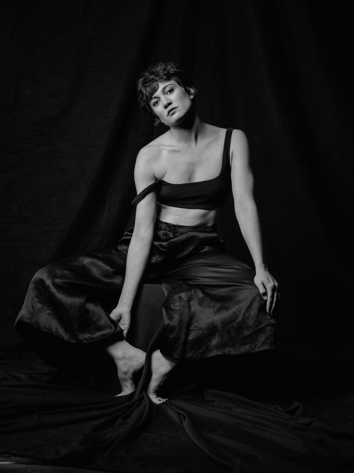 Milena Straube sitzend in Bustier und Satinhose, Schwarzweiß, Fashion-Strecke
