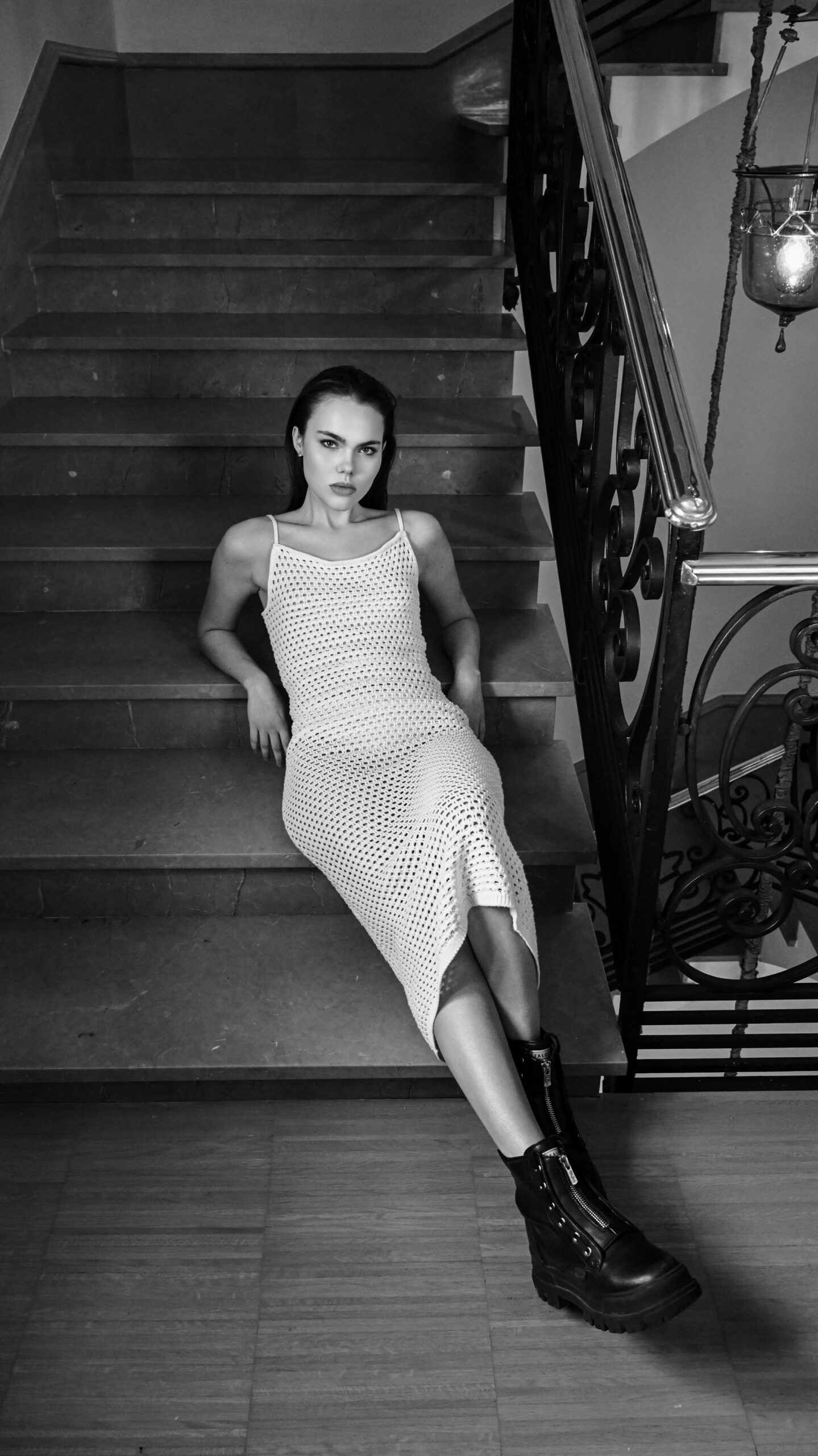 Kim Decker im Strickkleid auf einer Treppe, Schwarzweiß, Fashion-Strecke